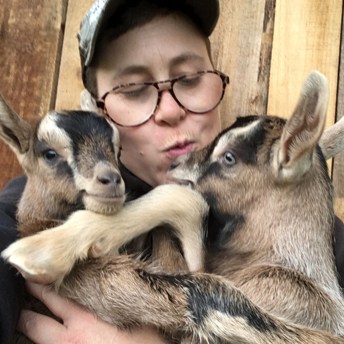 Rae Garringer holding and kissing baby goats