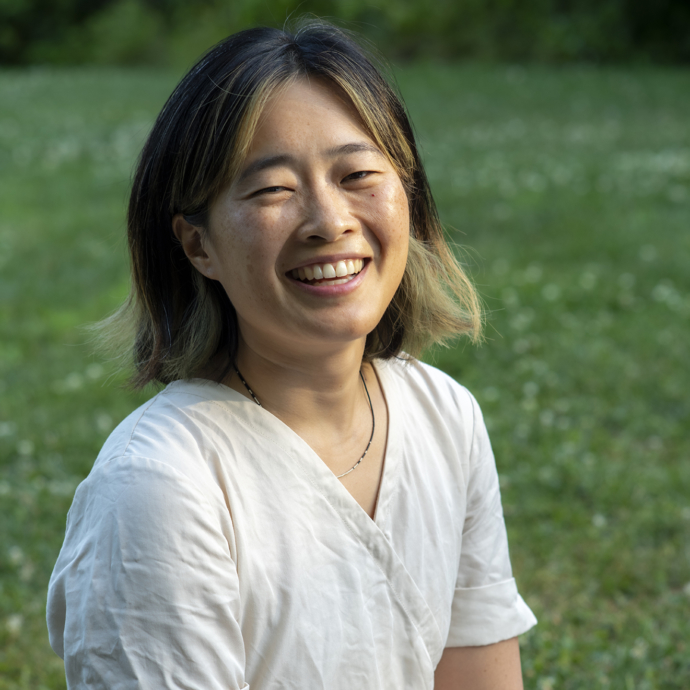 Ann Chen smiling in a white t-shirt in front of a green background